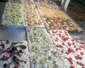 Pizze fresche esposte sul banco della Pizzeria al taglio Da Alex